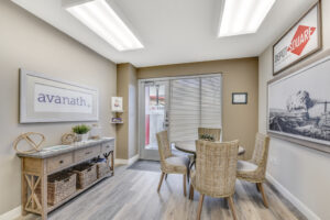 Interior Leasing Office, Wood floors, signage on front door, avanath signage upon entering, landscape paintings on walls, circular table with wicker chairs, rustic decor.